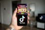 Mano sosteniendo móvil con juego de tragamonedas y logo de TikTok.